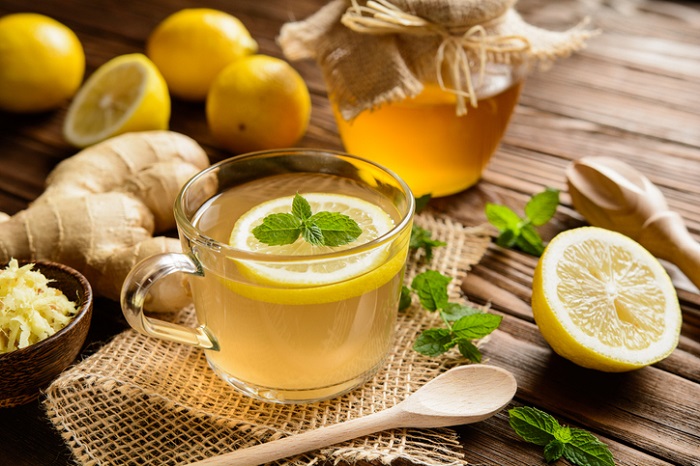 دمنوش زنجبیل تازه با تکه‌های زنجبیل و لیمو در فنجان شیشه‌ای