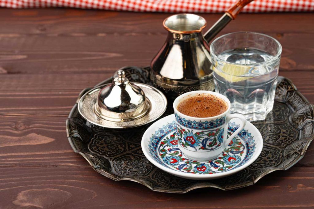 قهوه ترک شامل یک فنجان قهوه با کف، یک لیوان آب سرد